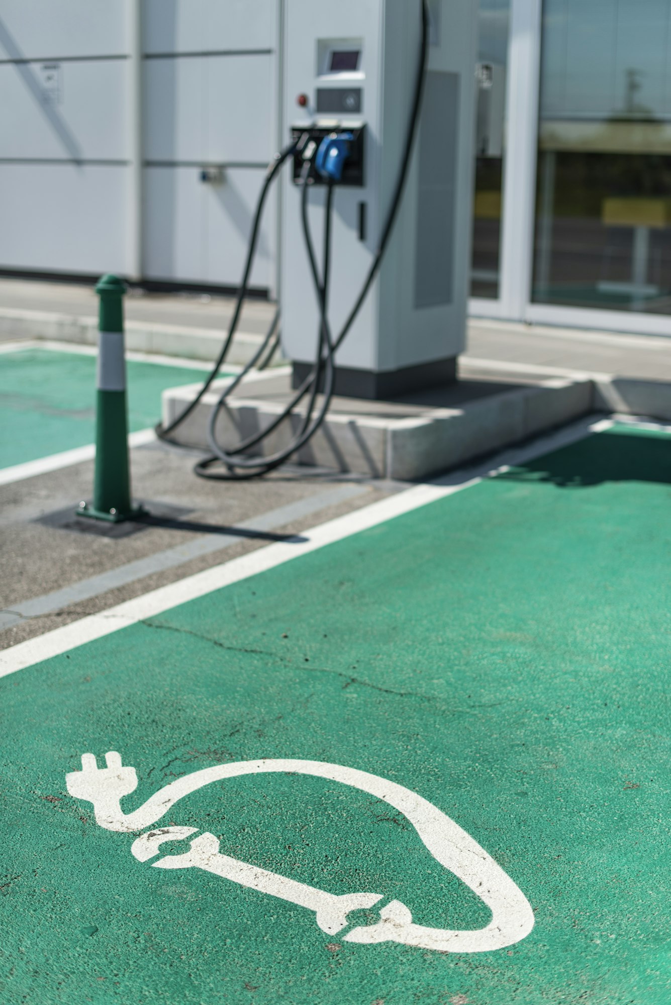 Electric charge station. Electric plug for charging cars. Car charging symbol painted on asphalt.